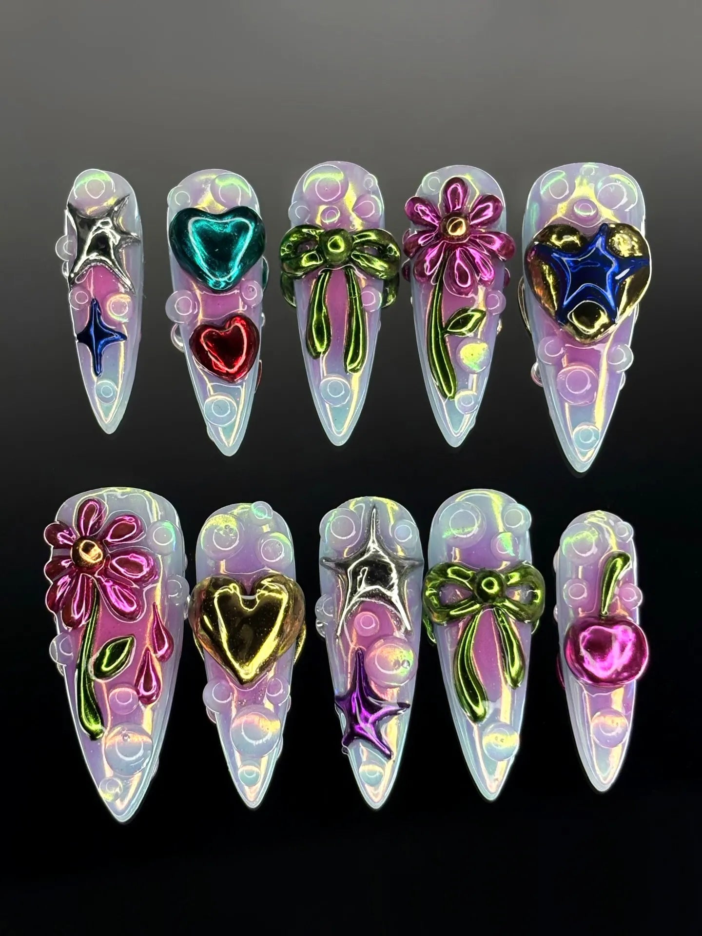 Handmade iridescent press-on nails with 3D metallic hearts, stars, bows, flowers, and cherries