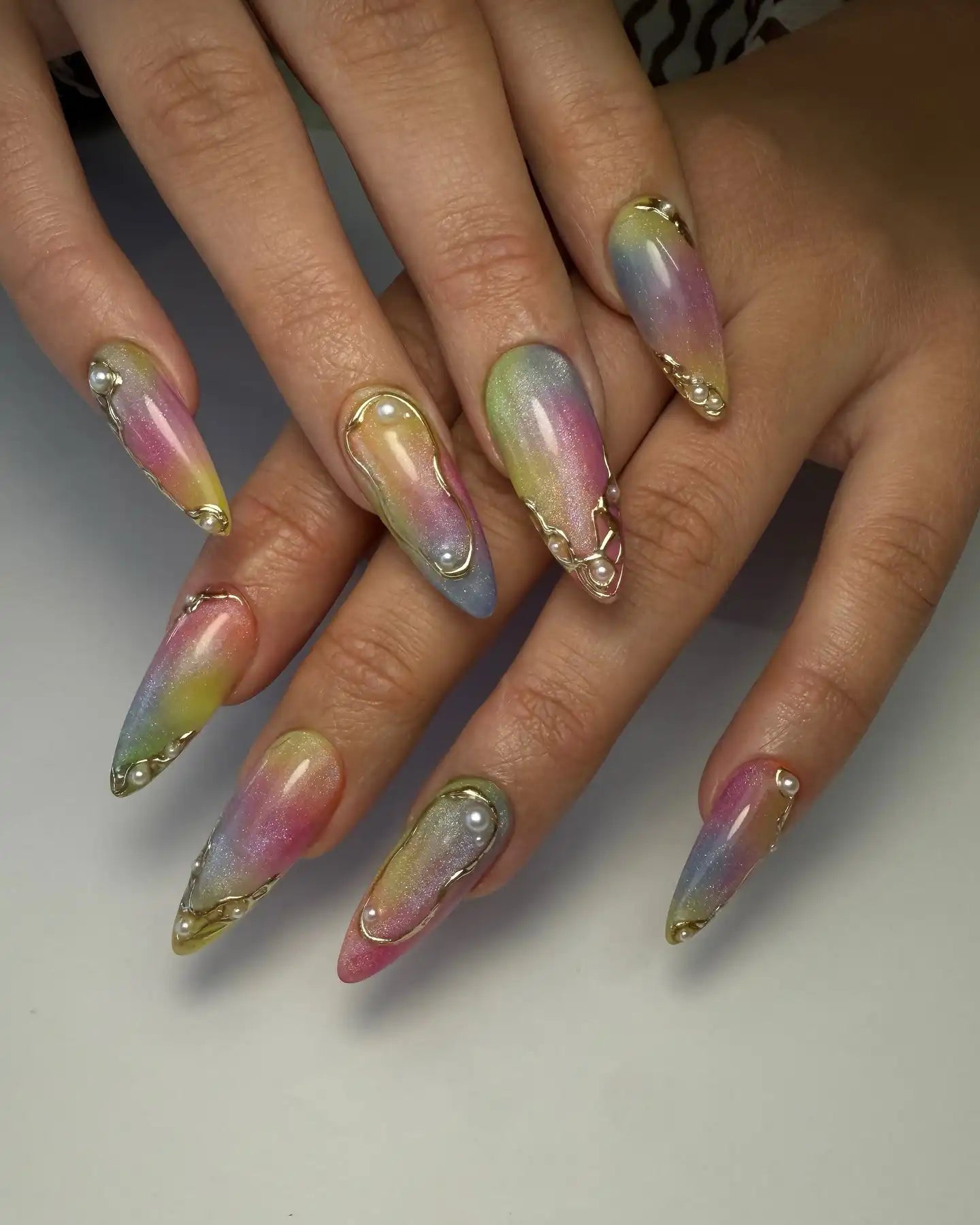 Handmade iridescent pastel press-on nails with 3D gold accents and pearl decorations.
