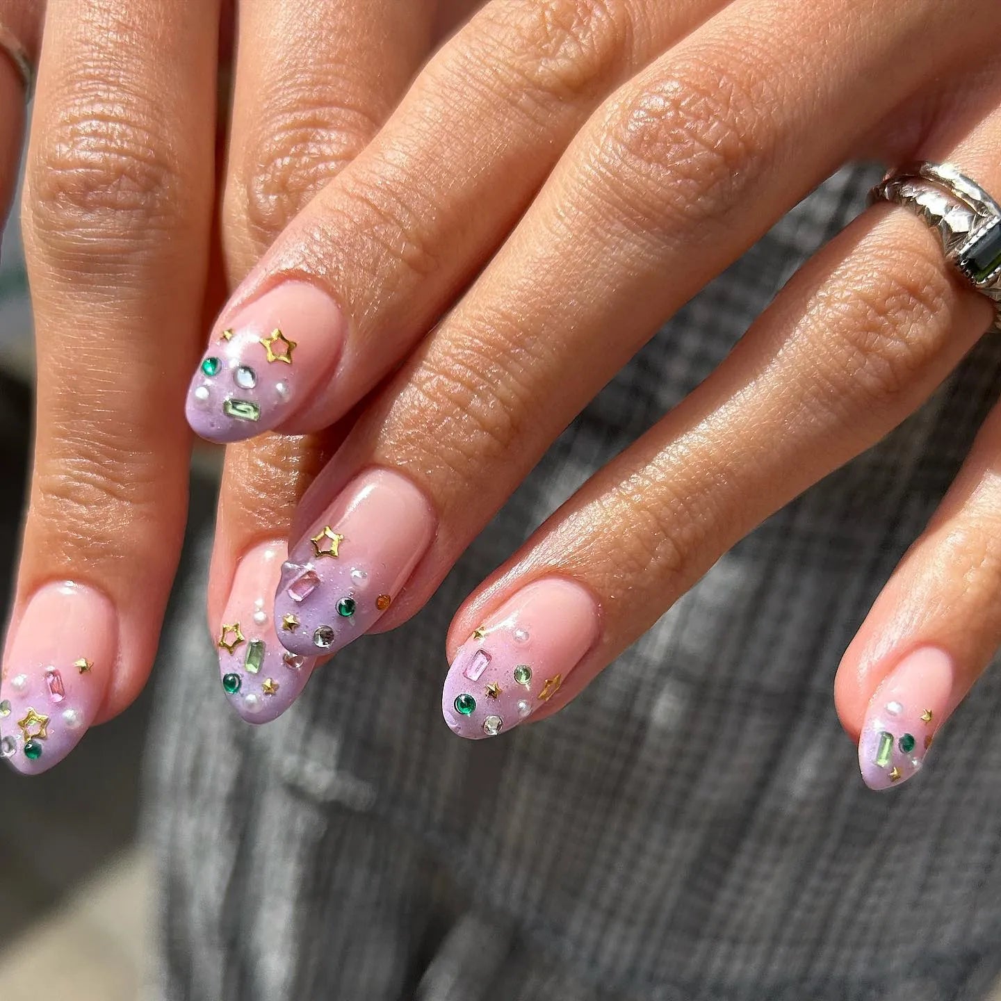 Hand with lavender ombre press-on nails decorated with gemstones and gold star accents