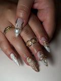 Hand with handmade coastal press-on nails featuring 3D shell, starfish, pearl and gold accents