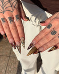 Hand with long luxury brown tortoise shell press-on nails, gold gem and floral accents