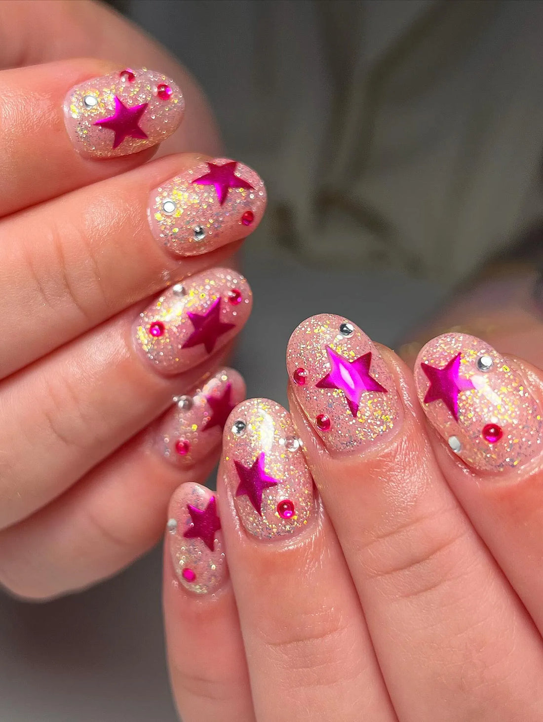 Handmade press-on nails with chunky gold glitter, magenta starburst and rhinestone accents