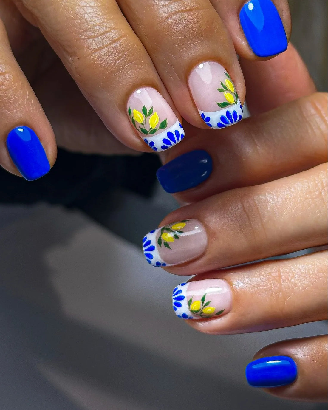 Handmade press-on nails with blue French tips, Mediterranean lemon and floral tile design.