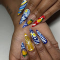 Hand with long stiletto press-on nails featuring Mediterranean lemon and blue white Talavera designs.