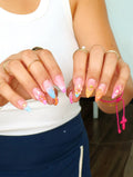 Hand with handmade press-on nails featuring mermaid shell, tropical floral, pearl, and ocean designs