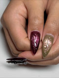 Hand holding metallic stiletto press-on nails with 3D raindrop water effect design.