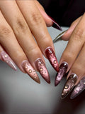 Hand with stiletto press-on nails featuring metallic cat-eye and 3D raindrop designs