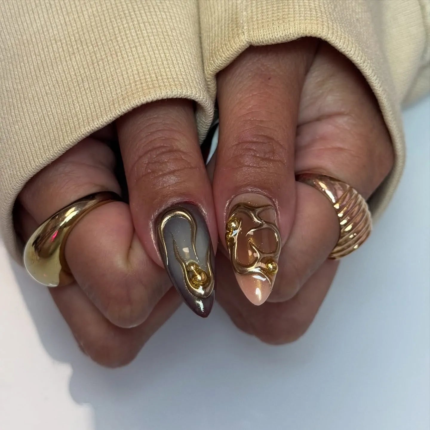 Hand displaying handmade press-on nails with tortoise shell, plaid, and gold studded designs.