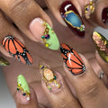 Handmade press-on nails with monarch butterfly designs, crystals, gemstones, and gold accents.