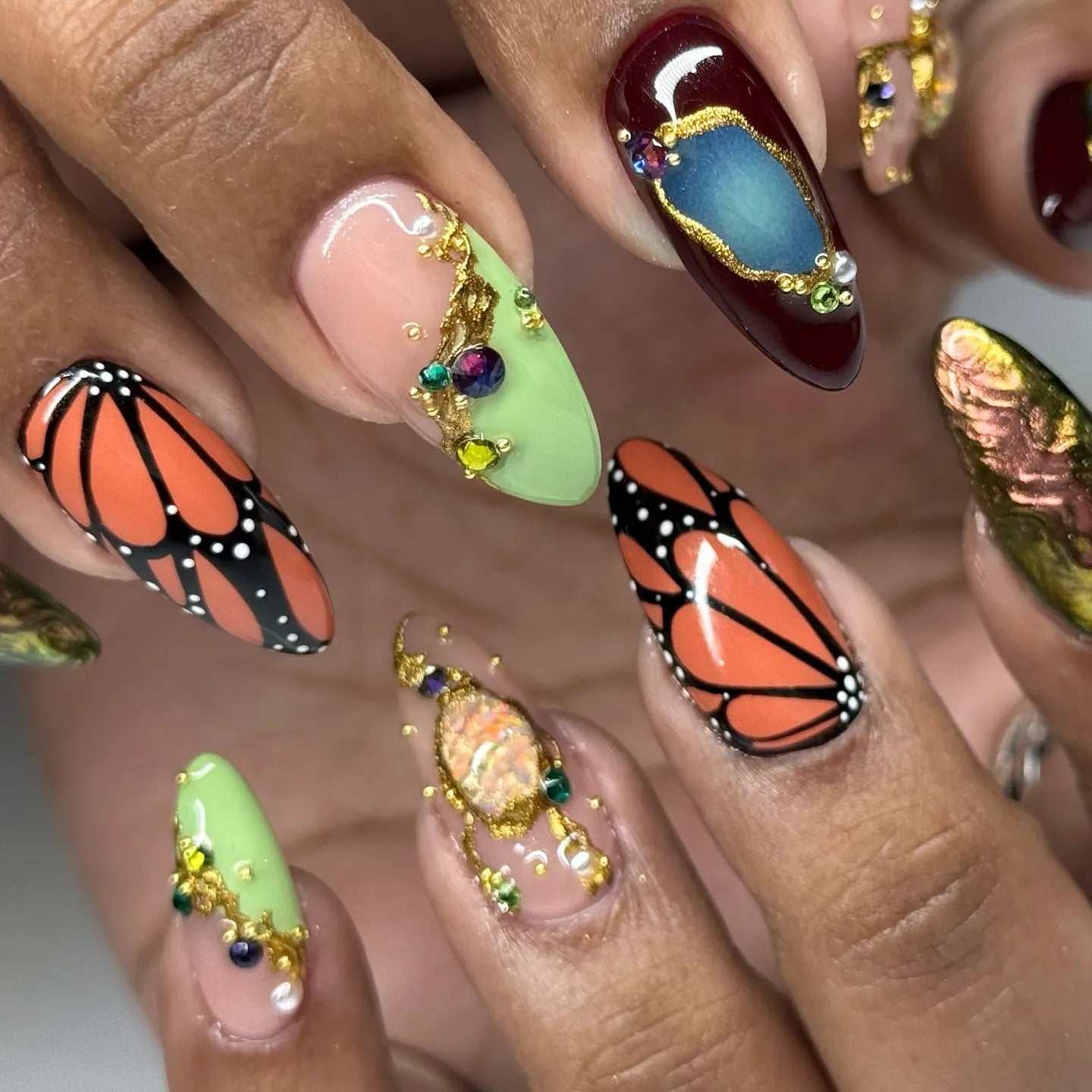 Handmade press-on nails with monarch butterfly designs, crystals, gemstones, and gold accents.