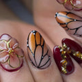 Handmade press-on nails with 3D amber floral designs, monarch butterfly wing art, and gold accents.