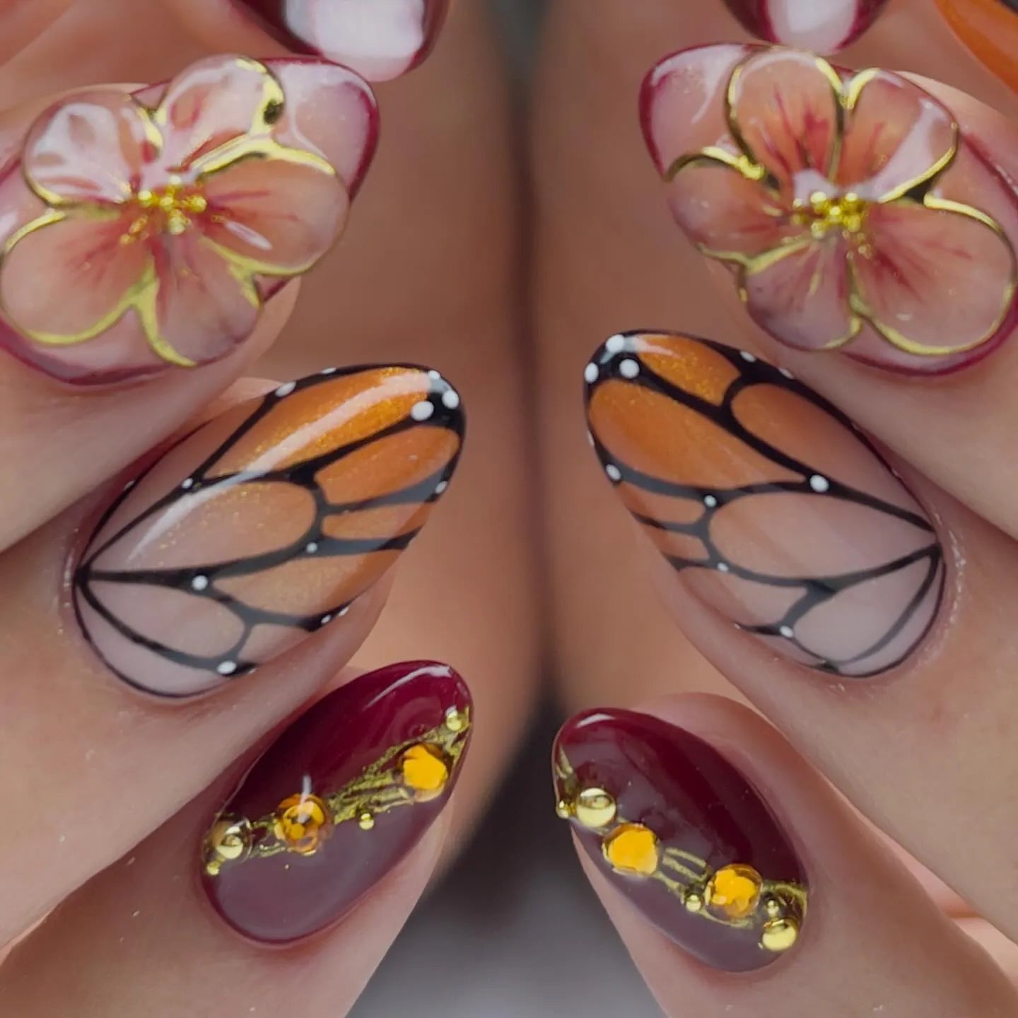 Handmade press-on nails with monarch butterfly wing, amber floral, and jewel accents