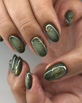 Hand with handmade olive green press-on nails featuring gold botanical accents