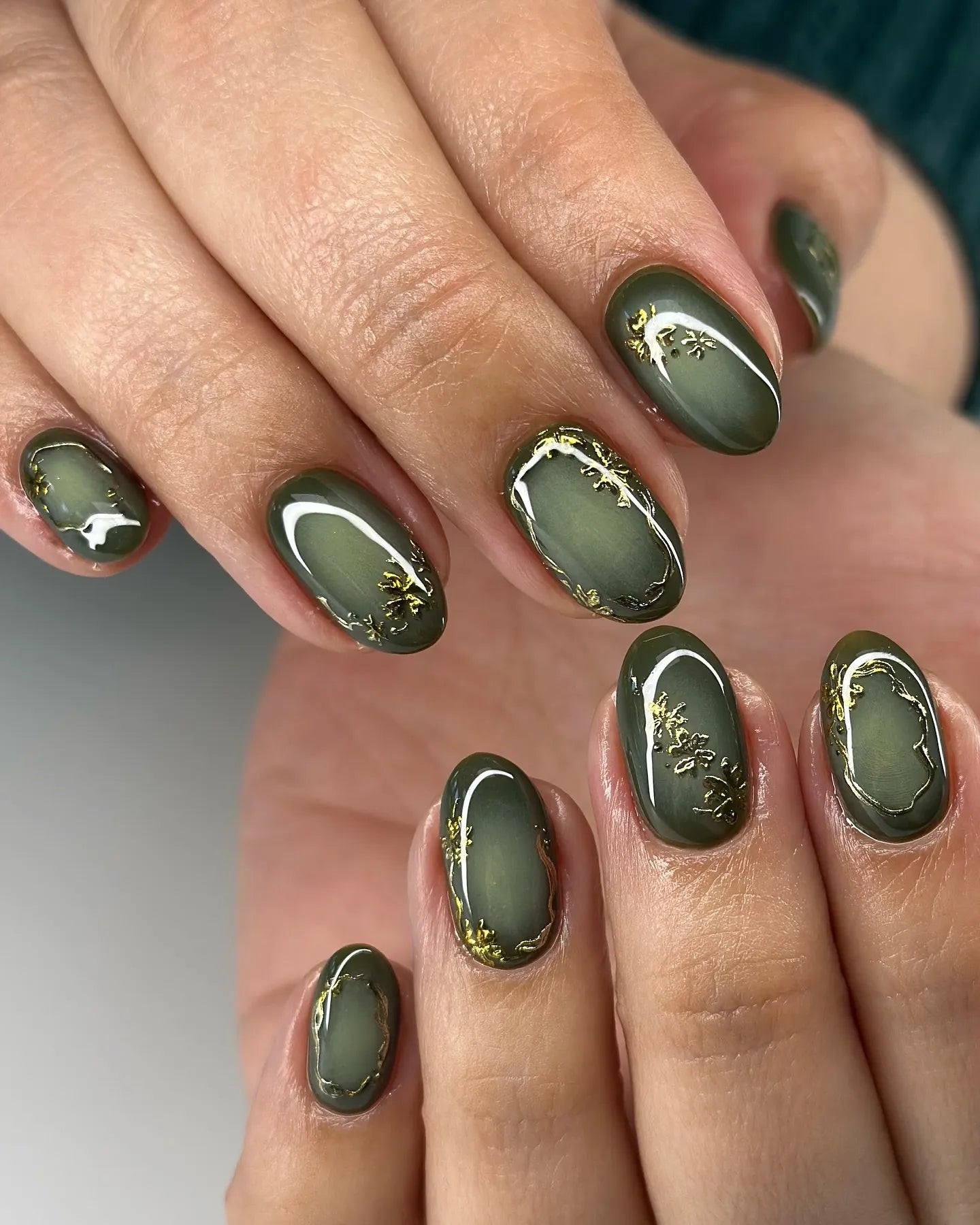 Handmade olive green press-on nails with gold botanical accents, glossy oval shape