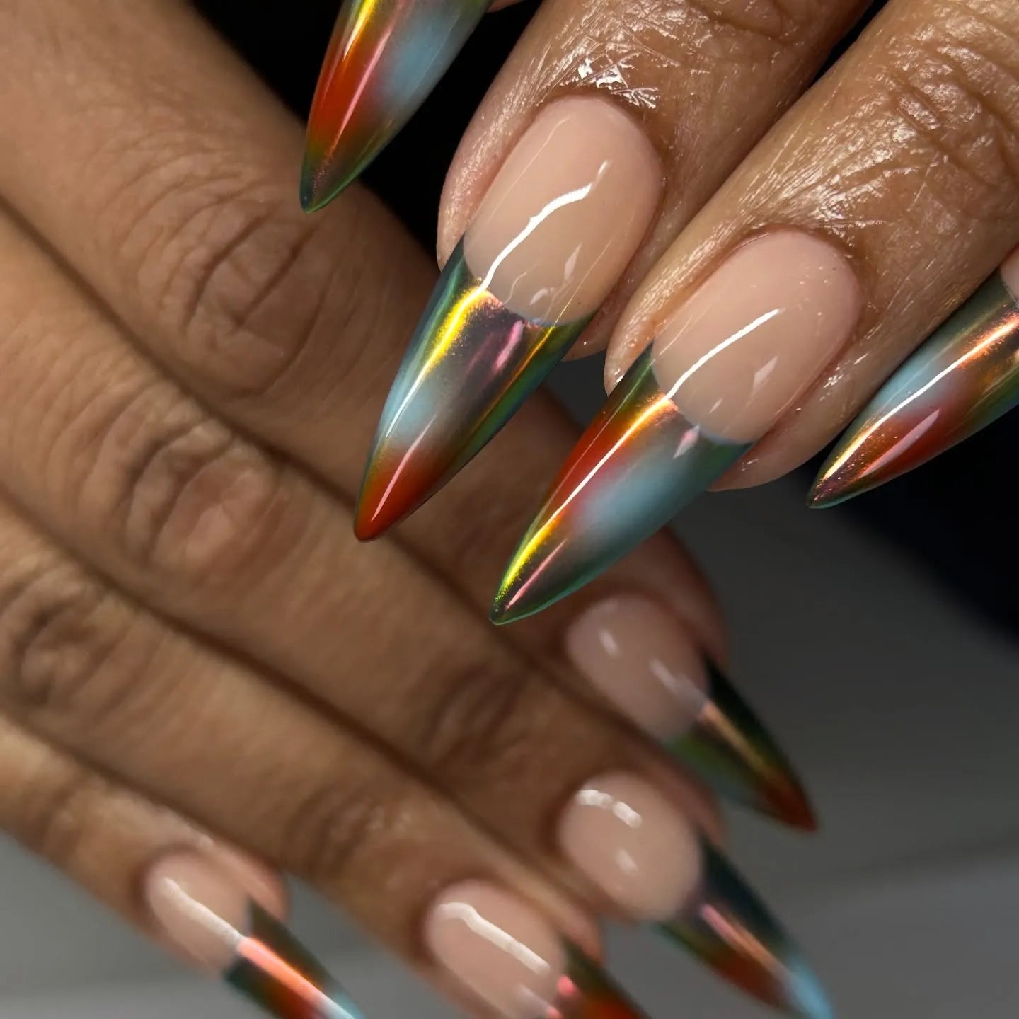 Hand with extra long stiletto press-on nails, multi-color chrome French tips