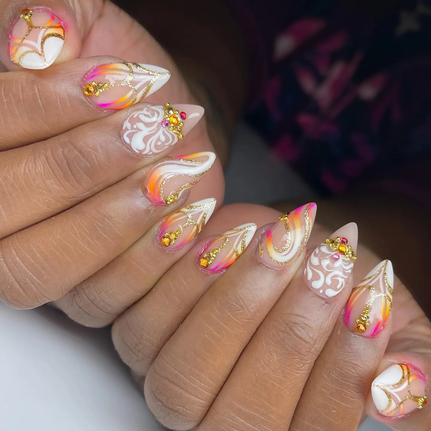 Handmade press-on nails with gold swirls, sunset gradient, and white crystal accents.
