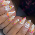 Handmade press-on nails with sunset gold swirls, white accents, and crystal embellishments.