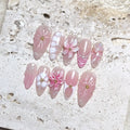 Handmade nude pink press-on nails with 3D petal flowers, pearls, and butterfly accents.