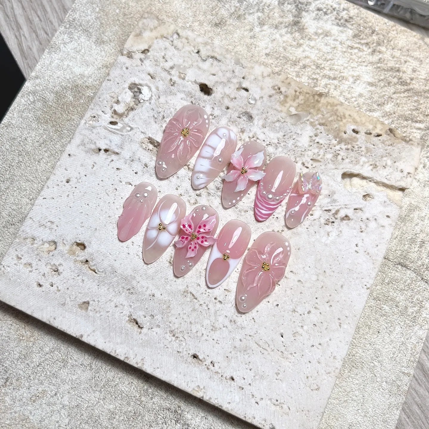Handmade nude pink press-on nails with 3D flower petals, pearls, and butterfly accents.