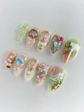 Handmade press-on nails with oriental floral designs, gold accents, and blue fan art.