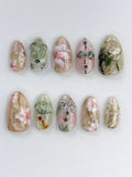 Handmade press-on nails with oriental floral designs, jade accents, gold shimmer, and fan art.