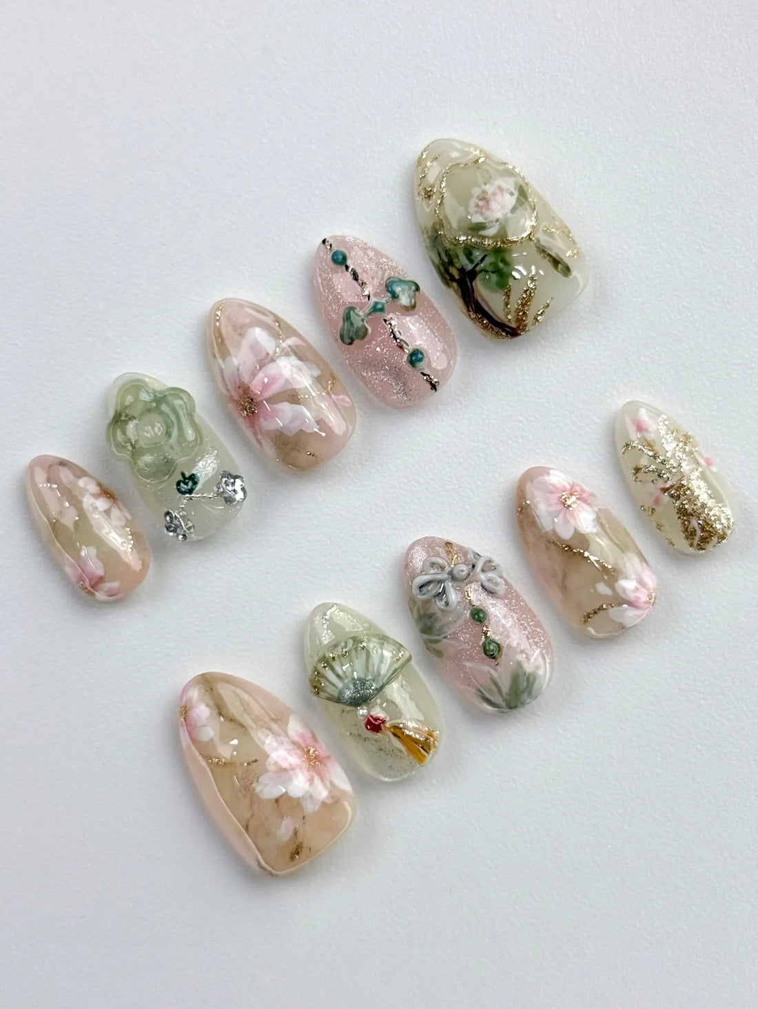 Handmade press-on nails with oriental floral designs, jade accents, gold shimmer, and fan art.