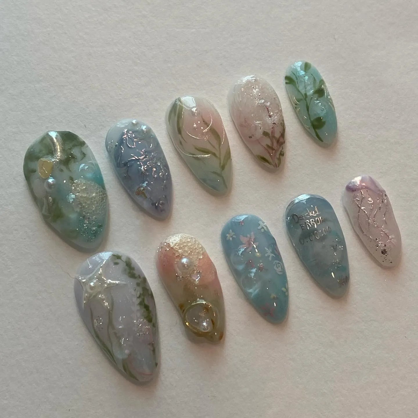 Handmade pale blue press-on nails with ocean, jellyfish, water lily, and silver accents
