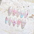 Handmade pastel press-on nails with butterfly, flower, bow, and pearl designs in pink and blue.