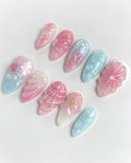 Handmade pastel jelly pink and blue press-on nails with 3D floral and shell designs.