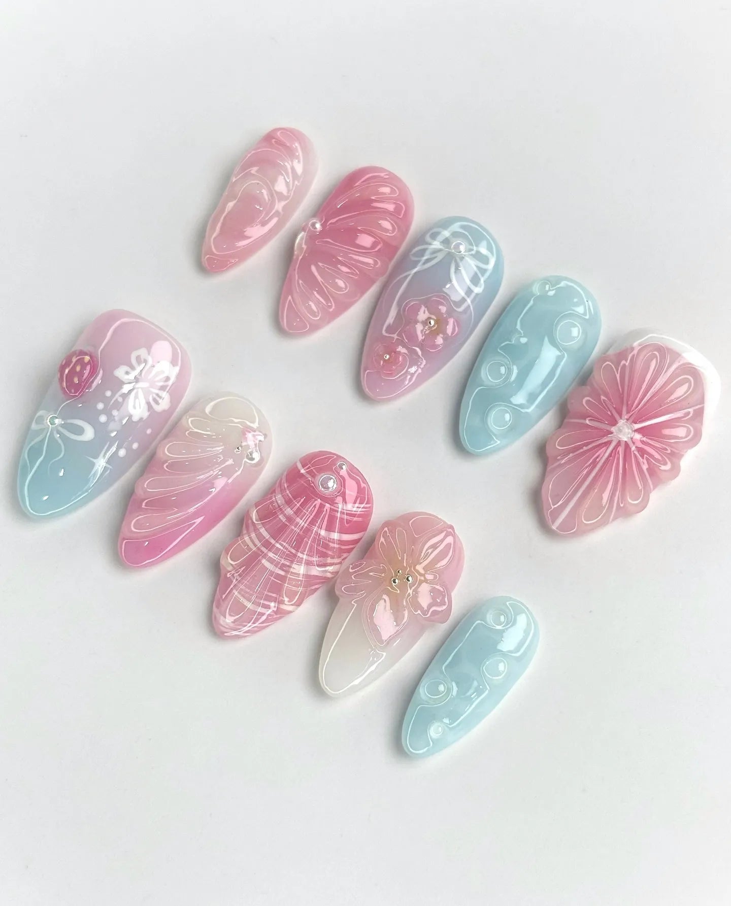 Handmade pastel jelly pink and blue press-on nails with 3D floral and shell designs.