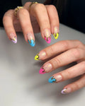 Hand with almond-shaped pastel neon drip press-on nails, gold chrome flake accents