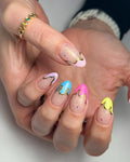 Hand with almond-shaped press-on nails, pastel neon drip art, gold chrome flake accents