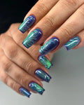 Hand with green and purple 3D swirl press-on nails, glossy and handmade design.