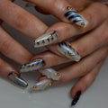 Hand with long handmade pearl white press-on nails, 3D swirl and gold stud accents, modern design