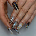 Hand with long, handmade pearl white press-on nails featuring 3D swirls, gold studs, and modern designs.