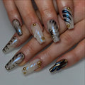 Handmade pearl white press-on nails with 3D swirl, gold studs, and modern black accents.