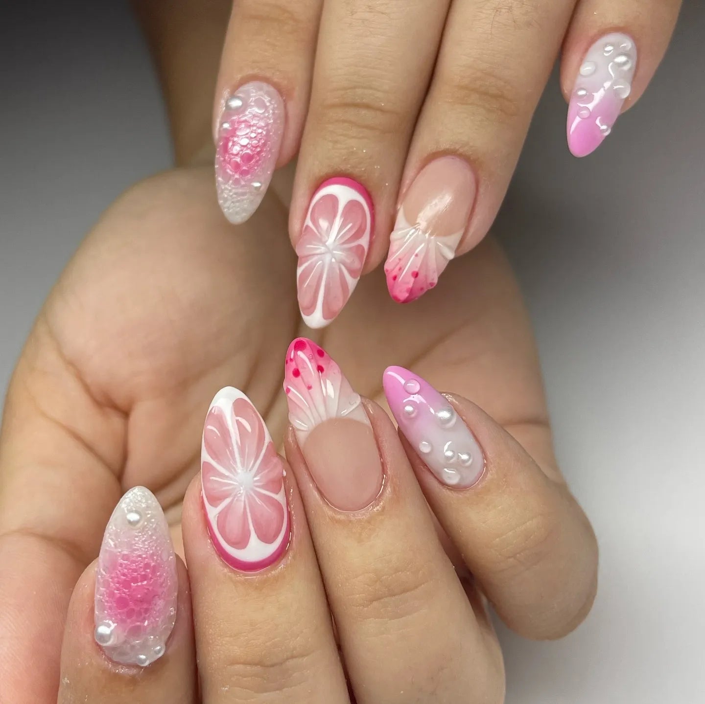 Hand with handmade pink 3D citrus blossom and pearl press-on nails, floral and textured design