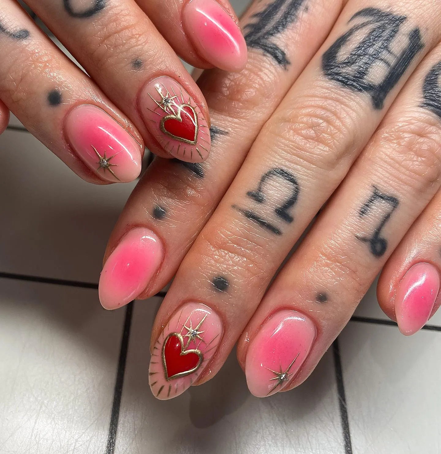 Handmade pink ombre press-on nails with gold starbursts and red heart accents