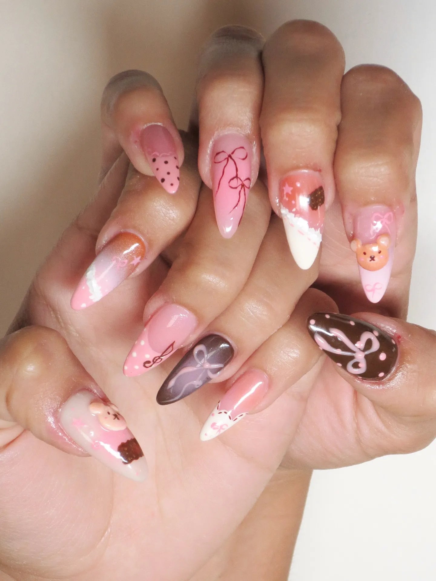 Handmade pink and brown press-on nails with 3D teddy bear, bows, lace, and polka dot designs