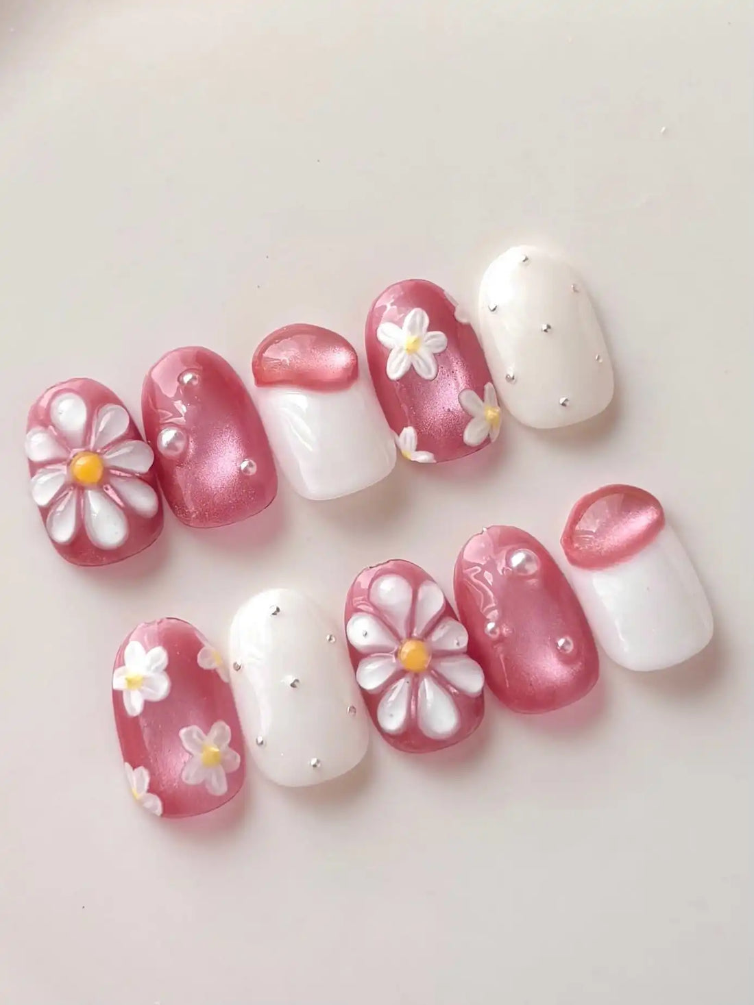 Handmade pink floral daisy shimmering pearl 3D press-on nails set on white background