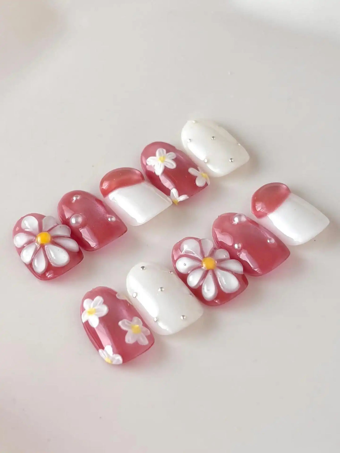 Handmade pink floral daisy shimmering pearl 3D press-on nails set on white background