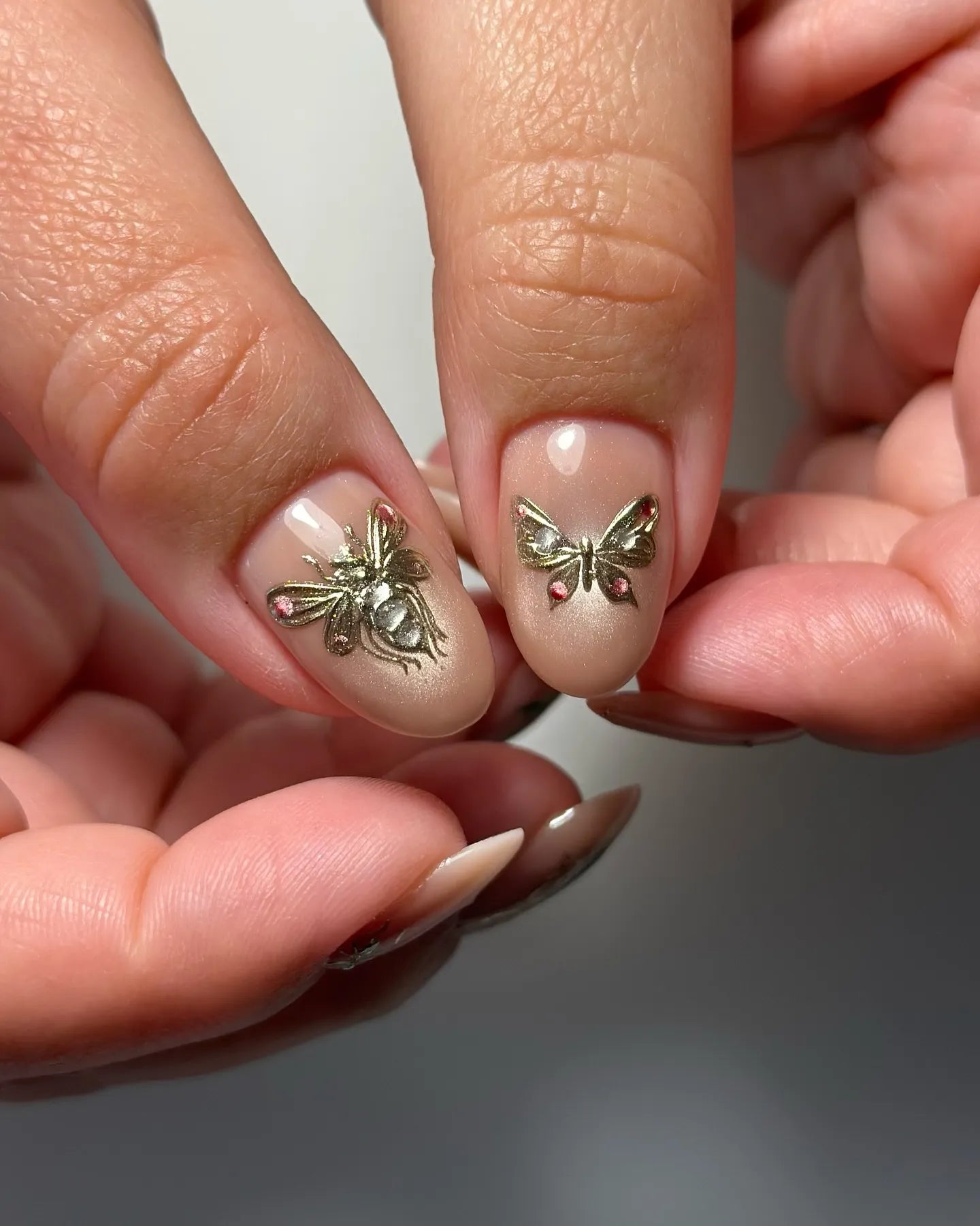Handmade nude pink press-on nails with gold bee and butterfly 3D charms, gemstone accents