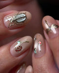 Handmade pink nude press-on nails with gold bug, butterfly, rose, and gemstone accents