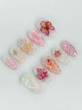 Handmade press-on nails with 3D pink orchid flowers and iridescent pearl accents.