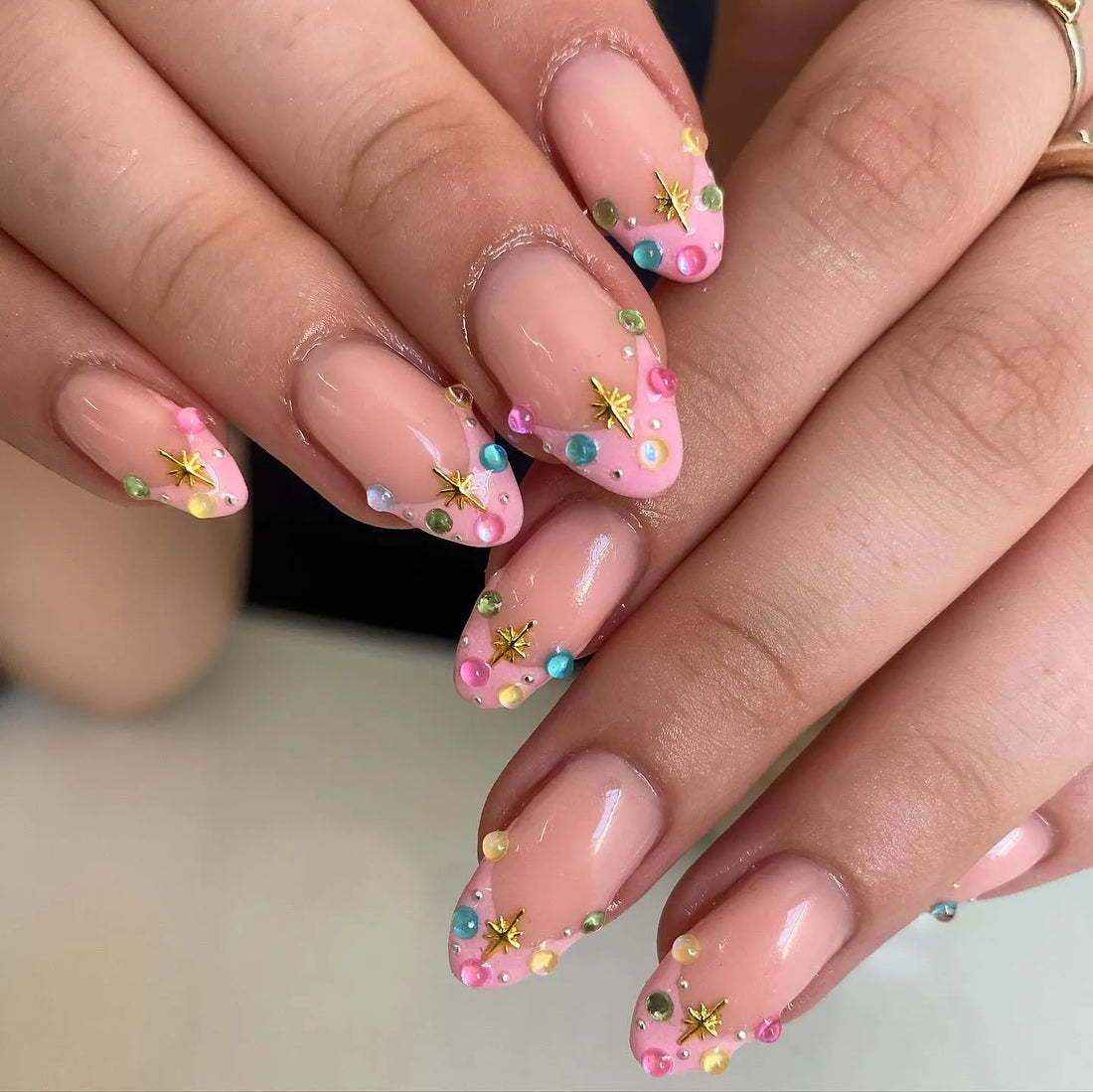 Handmade pink pastel press-on nails with gold star accents and colorful gemstone tips