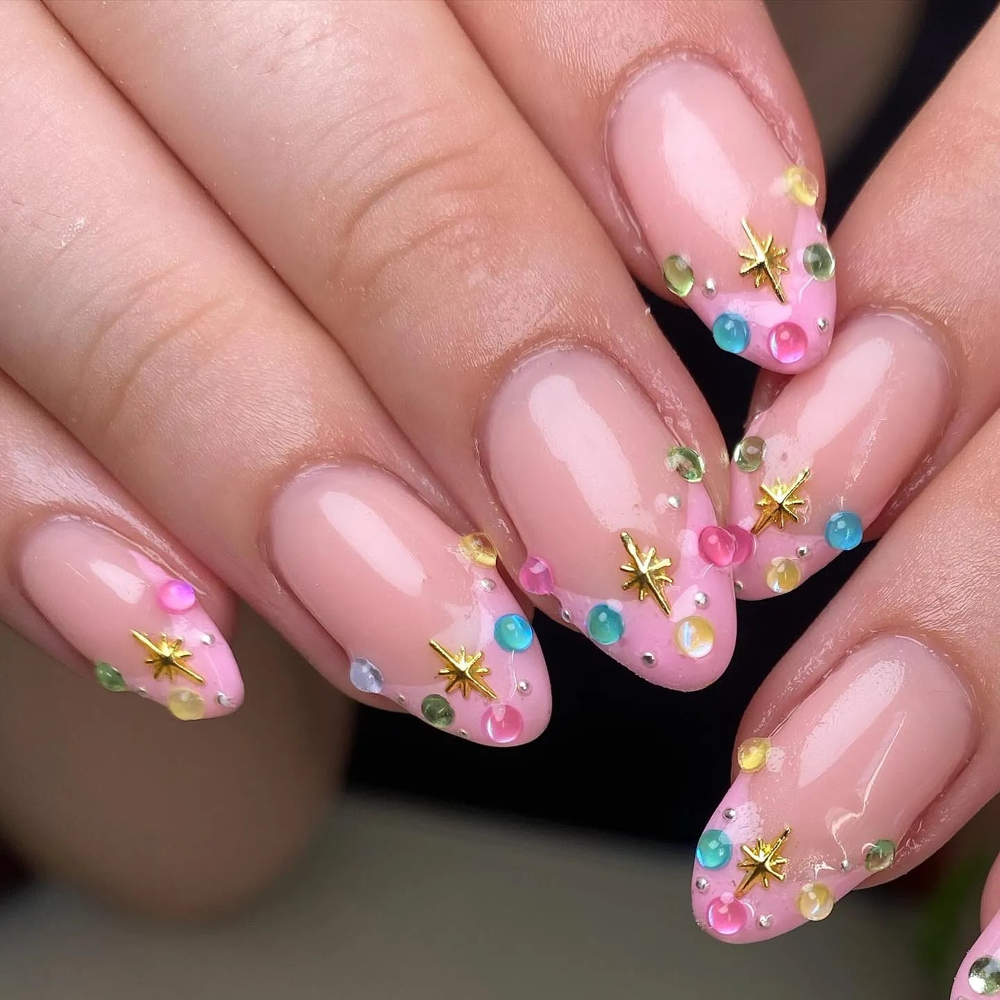 Handmade pink pastel press-on nails with colorful gemstones and gold star accents