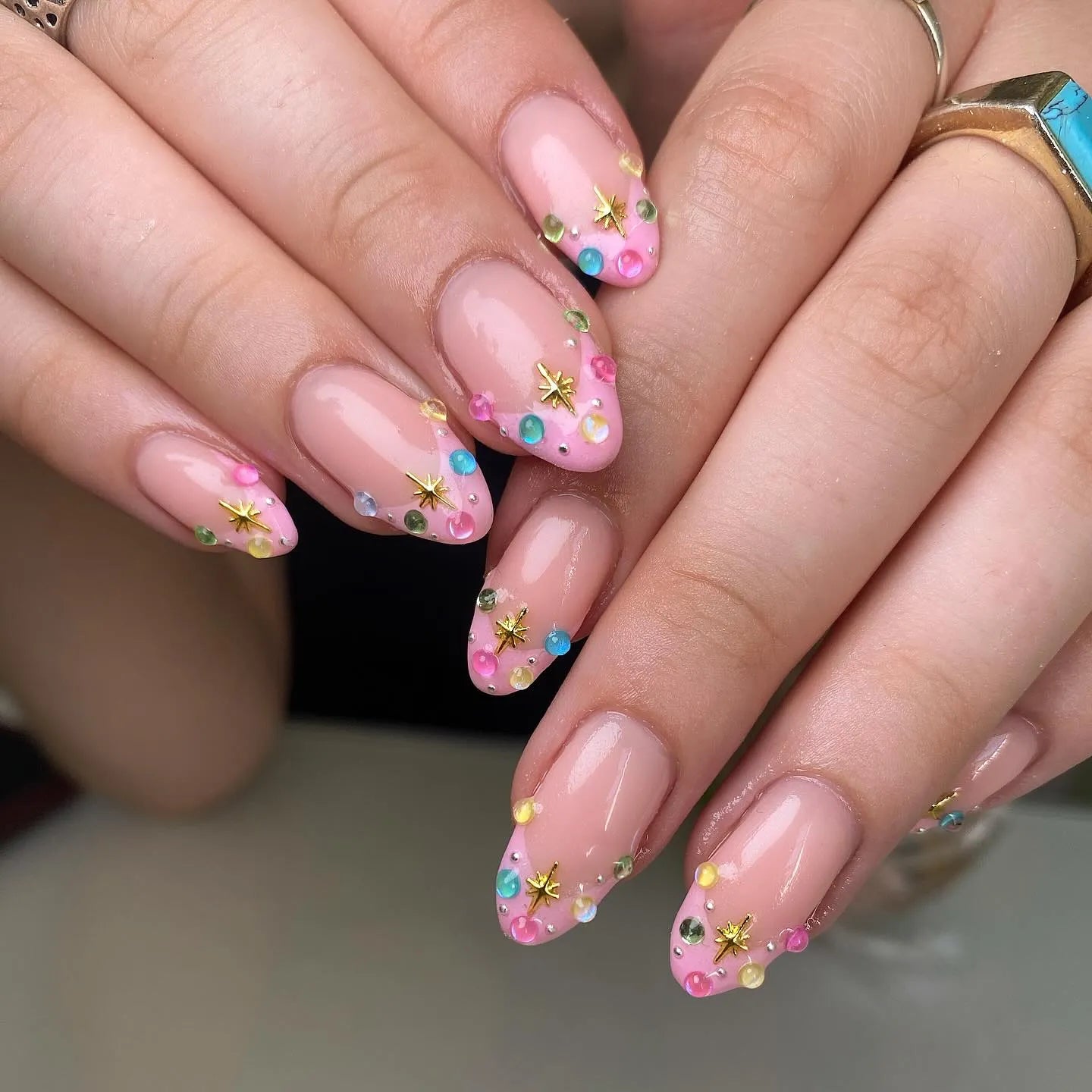Handmade pink pastel French tip press-on nails with colorful gemstones and gold star accents