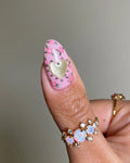 Handmade pink press-on nail with floral design and shimmering gold heart accent