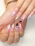 Hand with pink polka dot press-on nails, animal print accents, and 3D flower design.