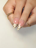 Hand holding stiletto-shaped press-on nails with nude base and white zebra print tips.